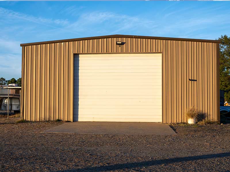 Tan steel building with one tall overhead door