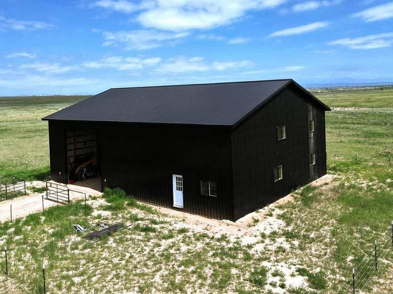 Black two-story barn on open grassland
