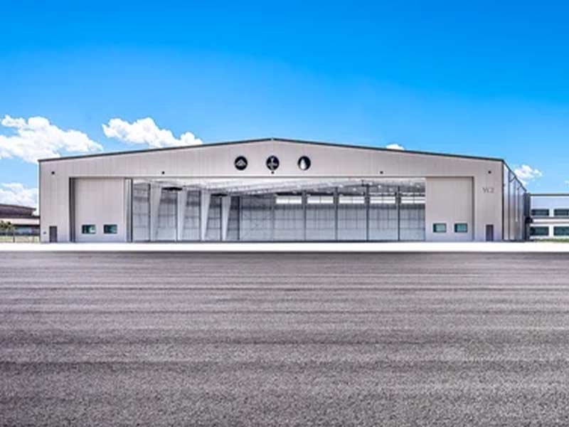 Wide clear-span steel building with a hangar-style door across the front
