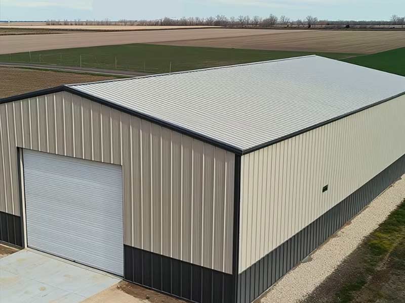 Tan and charcoal steel building with a roll-up door on a new concrete slab