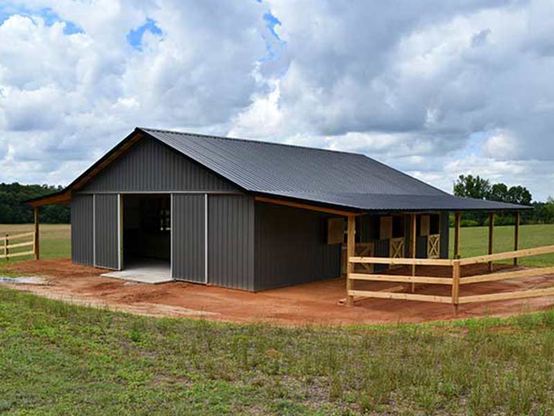 Charcoal post-frame barn and garage with a covered porch and wood rail fence
