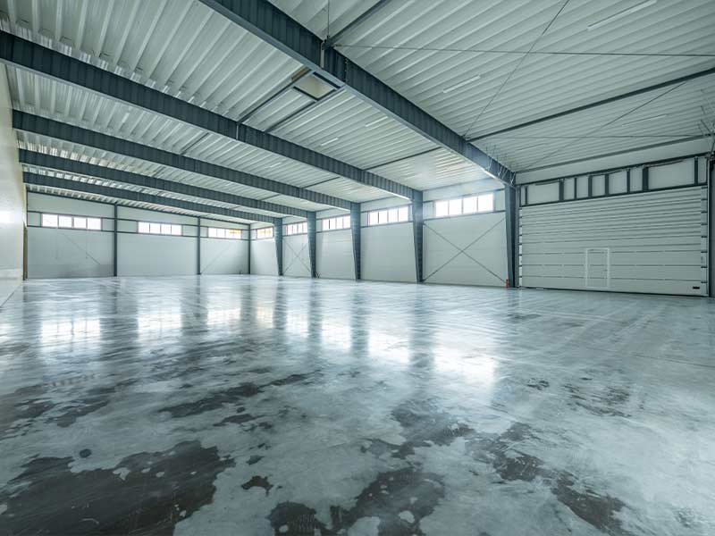Empty clear-span steel building interior with a polished concrete floor