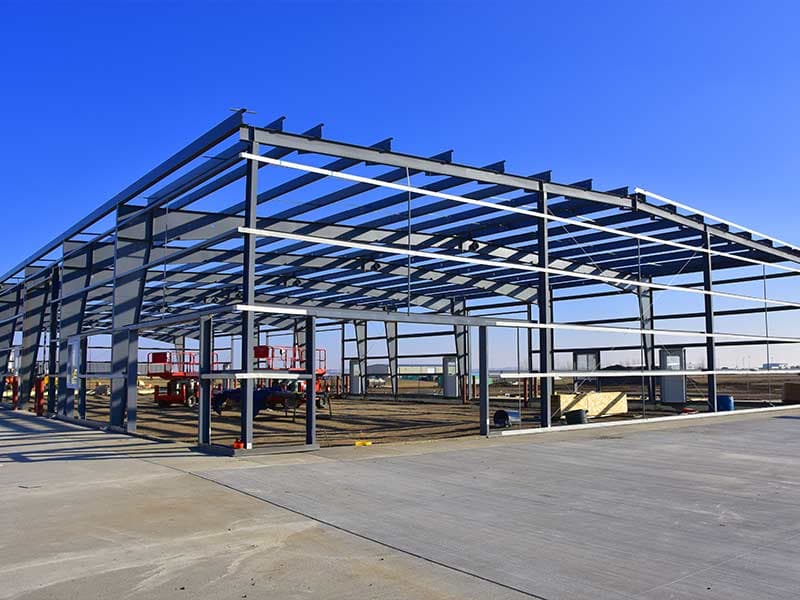 Large steel frame with rafters and purlins over a concrete slab